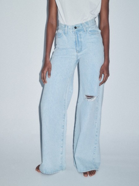 Mid blue jean ψηλόμεση παντελόνα, σε φαρδιά γραμμή, με ταμπά γαζιά, τετράγωνες τσέπες πίσω, φθορές στο ένα πόδι και κλείσιμο με κουμπί και κρυφό φερμουάρ Combos Knitwear  