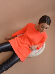 Πορτοκαλί fluo μακρυμάνικη πλεκτή loose-fit μπλούζα με ανοιχτή στρογγυλή λαιμόκοψη, σε αραιή πλέξη, ρεγκλάν μανικοκόλληση, μπροστινή τετράγωνη τσέπη και φαρδιά rib τελειώματα Kramma