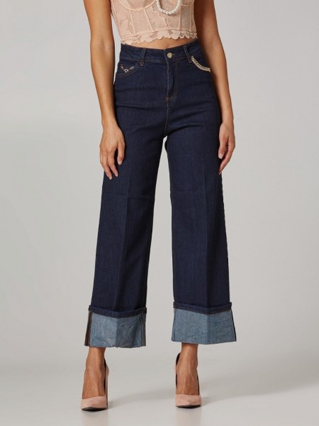 Blue jean ψηλόμεση cropped παντελόνα χωρίς ξεβάμματα, με μεγάλο ρεβέρ στο τελείωμα, κλείσιμο με φερμουάρ και χρυσό κουμπί και διακοσμητικές αλυσίδες στις τσέπες Lynne
