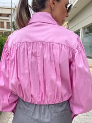Ροζ μακρυμάνικο ποπλίνα cropped πουκάμισο με πολλές πιέτες-σούρες, έντονα φαρδιά μανίκια, κλείσιμο με ιδιαίτερο κουμπί στην λαιμόκοψη και στις μανσέτες We coss