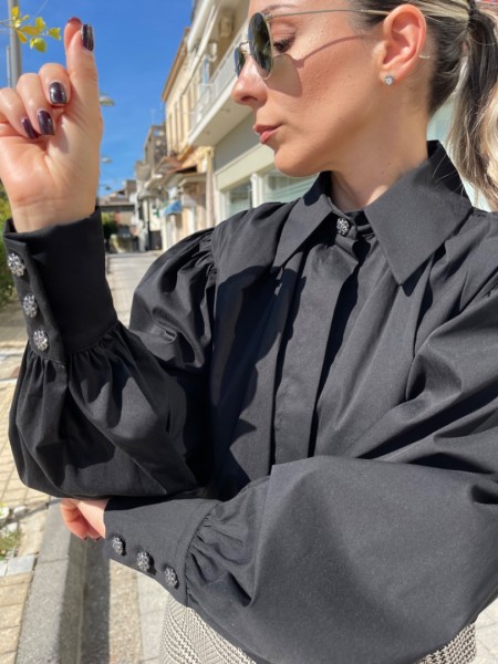 Μαύρο μακρυμάνικο ποπλίνα cropped πουκάμισο με πολλές πιέτες-σούρες, έντονα φαρδιά μανίκια, κλείσιμο με ιδιαίτερο κουμπί στην λαιμόκοψη και στις μανσέτες We coss