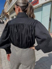 Μαύρο μακρυμάνικο ποπλίνα cropped πουκάμισο με πολλές πιέτες-σούρες, έντονα φαρδιά μανίκια, κλείσιμο με ιδιαίτερο κουμπί στην λαιμόκοψη και στις μανσέτες We coss