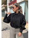 Μαύρο μακρυμάνικο ποπλίνα cropped πουκάμισο με πολλές πιέτες-σούρες, έντονα φαρδιά μανίκια, κλείσιμο με ιδιαίτερο κουμπί στην λαιμόκοψη και στις μανσέτες We coss