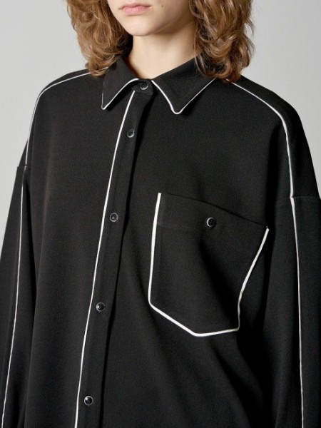 Μαύρο μακρυμάνικο oversized πουκάμισο σε κρεπ ελαστική ύφανση, με μπροστινή μεγάλη τσέπη, λευκά διακοσμητικά ρέλια και στρογγυλεμένο τελείωμα Access