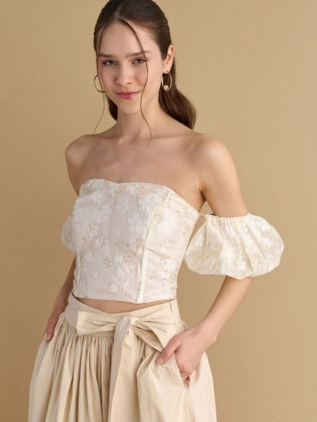 Εκρού δαντελένια strapless μπλούζα με χρυσές λεπτομέρειες, αποσπώμενα balloon μανίκια και κλείσιμο με εξωτερικό φερμουάρ attrattivo