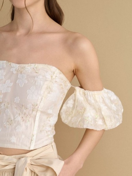 Εκρού δαντελένια strapless μπλούζα με χρυσές λεπτομέρειες, αποσπώμενα balloon μανίκια και κλείσιμο με εξωτερικό φερμουάρ attrattivo