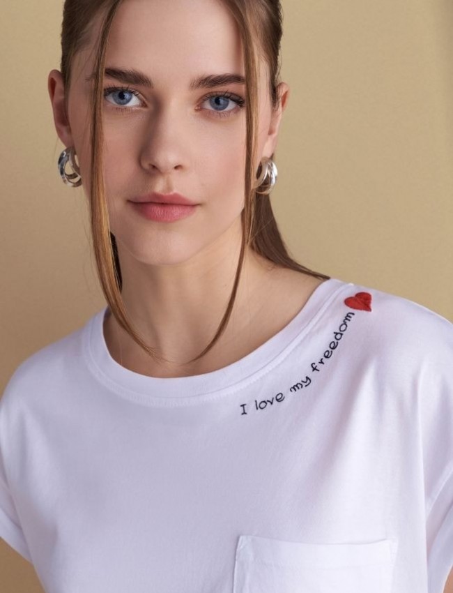 Λευκό βαμβακερό κοντομάνικο t-shirt, με κλειστή στρογγυλή λαιμόκοψη, σε τετράγωνη γραμμή, με τετράγωνη τσέπη μπροστά και κεντημένο λογότυπο "I love my freedom"Attrattivo  