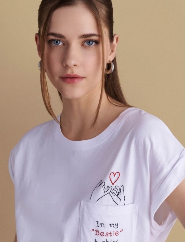 Λευκό βαμβακερό κοντομάνικο t-shirt, με ανοιχτή στρογγυλή λαιμόκοψη, με τετράγωνη τσέπη μπροστά και κεντημένο λογότυπο "In my "Bestie" t-shirt" Attrattivo 