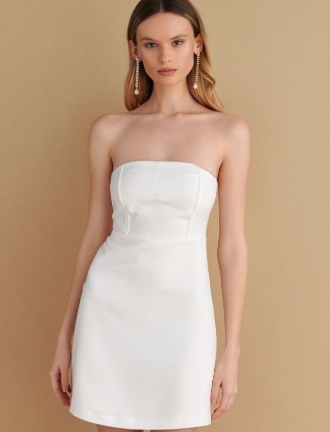 Λευκό strapless κοντό φόρεμα σε Α-γραμμή, διακοσμητικά strass στο πάνω μέρος, αποσπώμενες λεπτές τιράντες και κλείσιμο κε κρυφό φερμουάρ στην πλάτη Attrattivo