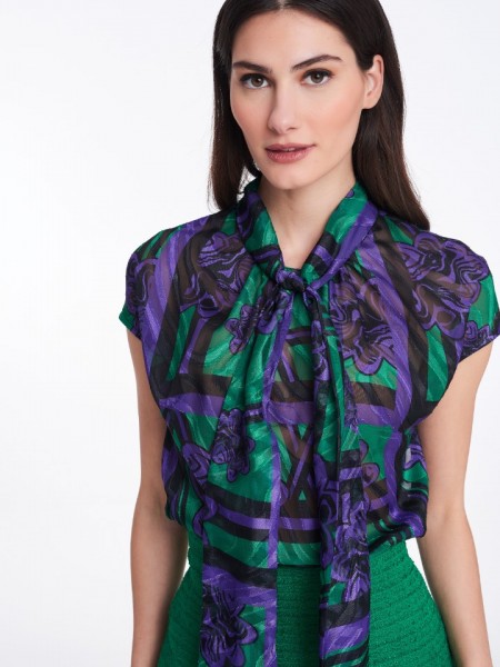 Floral printed μωβ-πράσινη κοντομάνικη ημιδιάφανη μπλούζα, με ιδιαίτερο δέσιμο με φιιόγκο στν λαιμό σε μεσάτη γραμμή, με εσωτερικό αποσπώμενο top και κλείσιμο με διπλό κουμπί ψηλά στο λαιμό Badoo