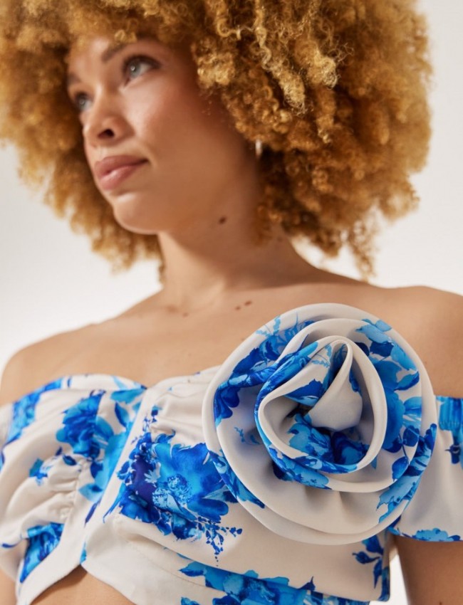 Floral printed γαλάζια κοντομάνικη cropped μπλούζα, με λάστιχο στους έξω ώμους, σούρες στο μπούστο και κλείσιμο με χρυσό φερμουάρ πίσω Enzzo 