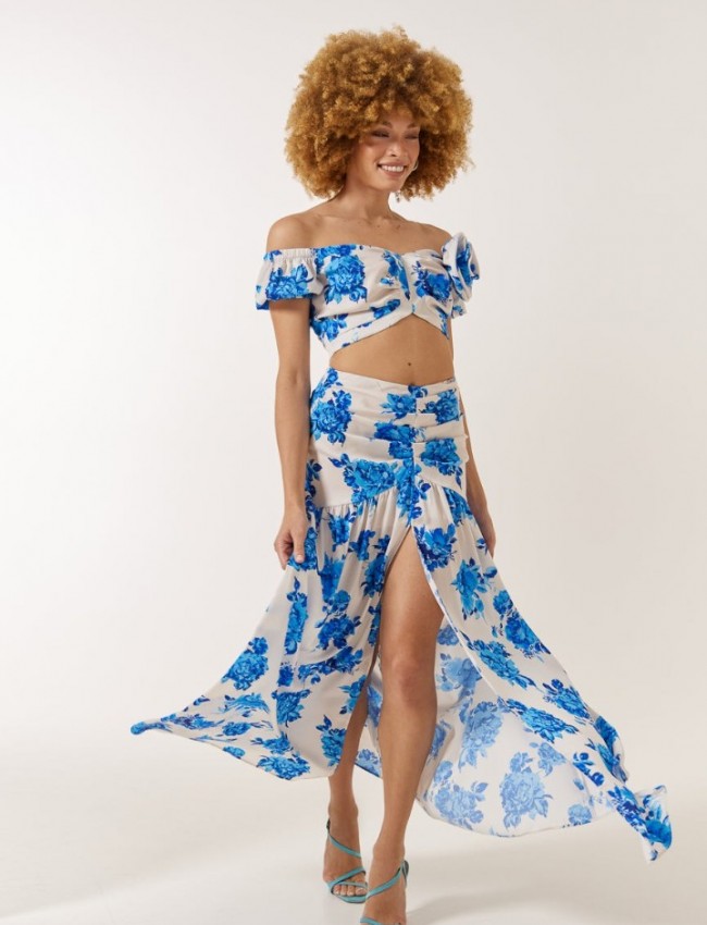 Floral printed γαλάζια ψηλόμεση maxi φούστα, με σκίσιμο μπροστά, αποσπώμενο υφασμάτινο λουλούδι και κλείσιμο με κρυφό φερμουάρ στο πλάι Enzzo 