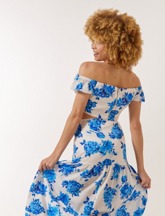 Floral printed γαλάζια ψηλόμεση maxi φούστα, με σκίσιμο μπροστά, αποσπώμενο υφασμάτινο λουλούδι και κλείσιμο με κρυφό φερμουάρ στο πλάι Enzzo 