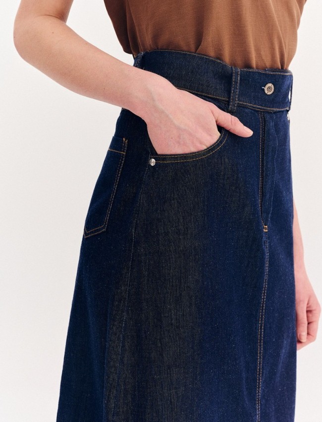 Blue jean ψηλόμεση midi φούστα, σε Α γραμμή, με ταμπά διακοσμητικά γαζιά, τετράγωνες τσέπες πίσω, κλείσιμο με κουμπί και κρυφό φερμουάρ μπροστά και αποσπώμενη ζώνη Forel 