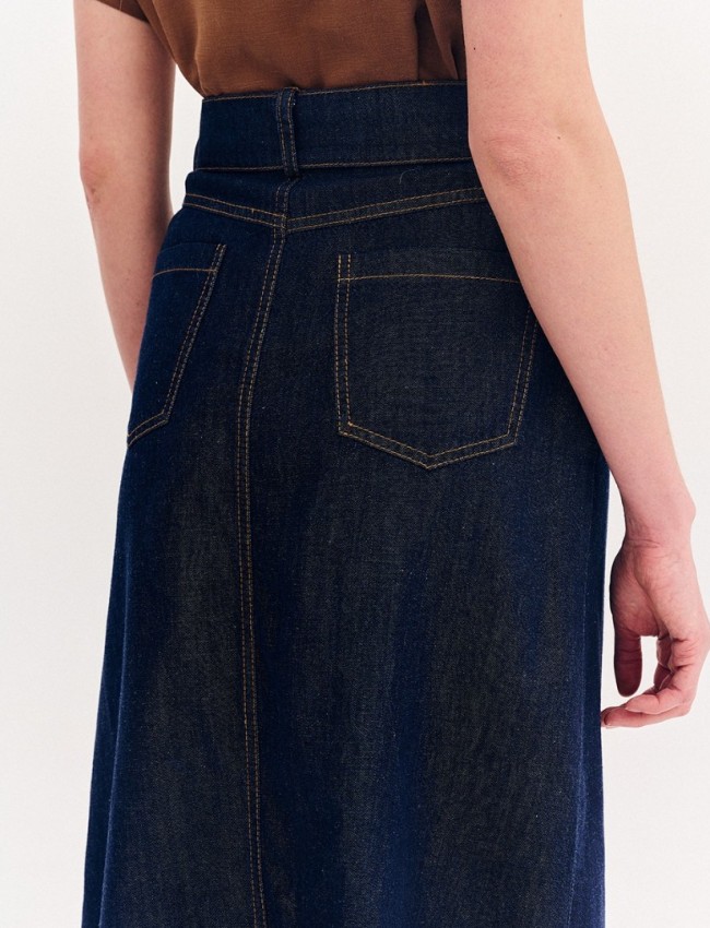 Blue jean ψηλόμεση midi φούστα, σε Α γραμμή, με ταμπά διακοσμητικά γαζιά, τετράγωνες τσέπες πίσω, κλείσιμο με κουμπί και κρυφό φερμουάρ μπροστά και αποσπώμενη ζώνη Forel 