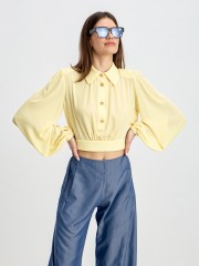 Κίτρινο μακρυμάνικο cropped μουσελίνα πουκάμισο με πέτο γιακά, χρυ΄σά κουμπιά κλείσιμο μπροστά και άνοιγμα στην πλάτη με ρυθμιζόμεο δέσιμο στο τελείωμα Innocent