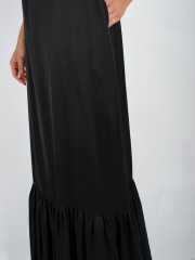 Μαύρο ματ σατέν maxi αμάνικο φόρεμα με λεπτή ρυθμιζόμενη τιράντα, μικρές σούρες μπροστά, πλαϊνές τσέπες και μεγάλο βολάν στο τελείωμα Vener